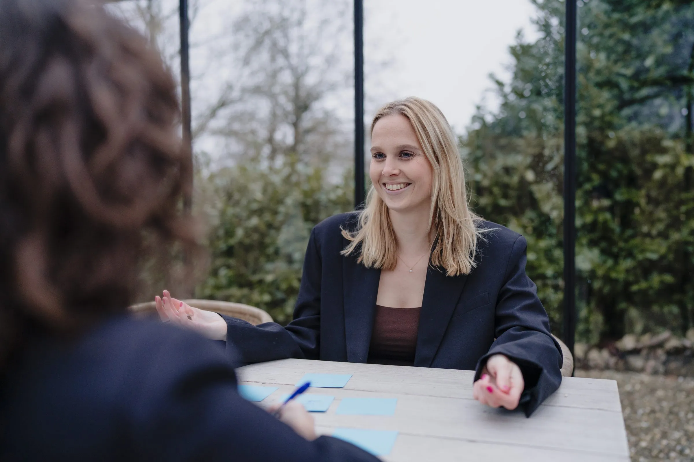 Imke in gesprek aan een tafel buiten, in het groen