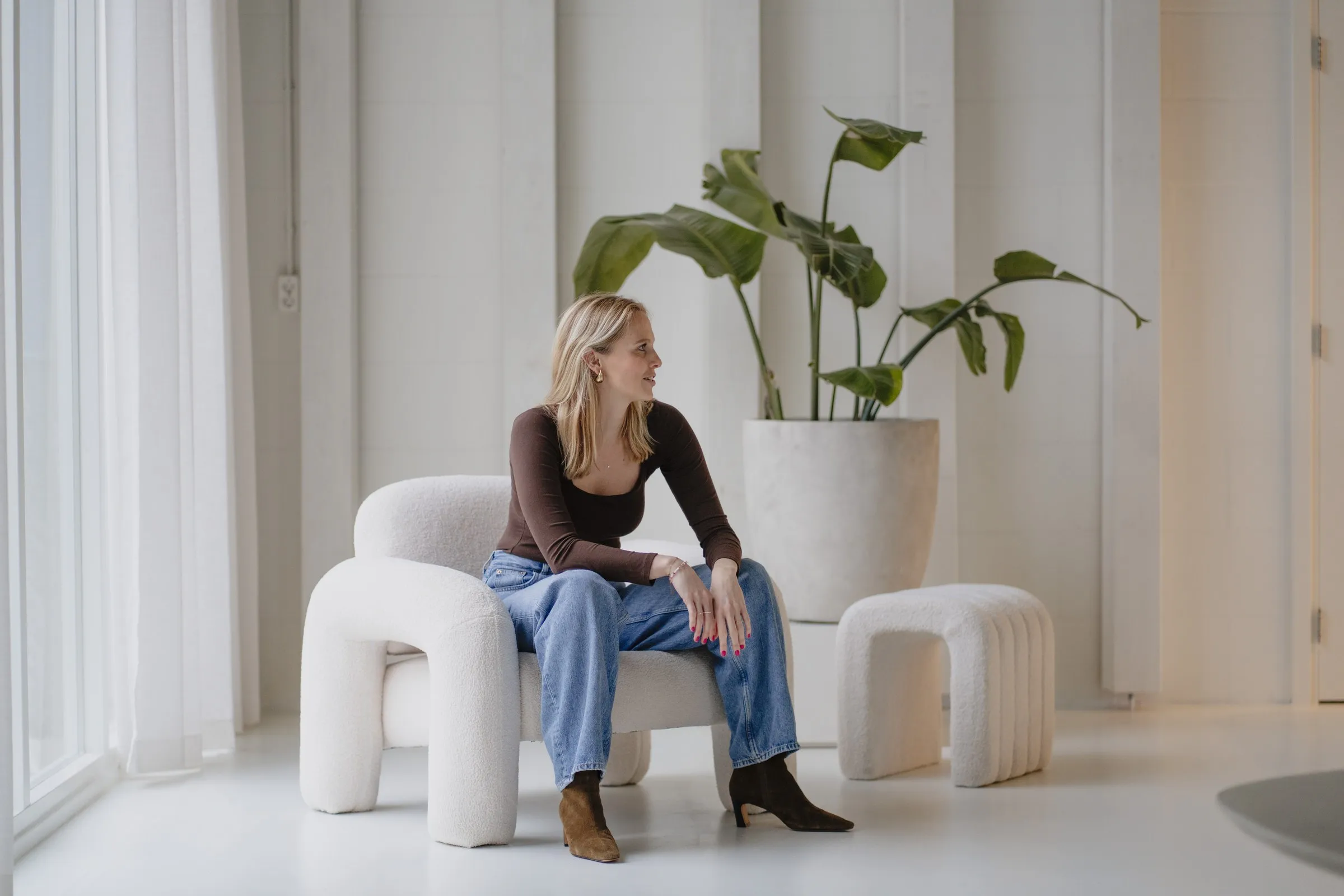 Imke zit ontspannen in een lichte fauteuil en kijkt naar buiten