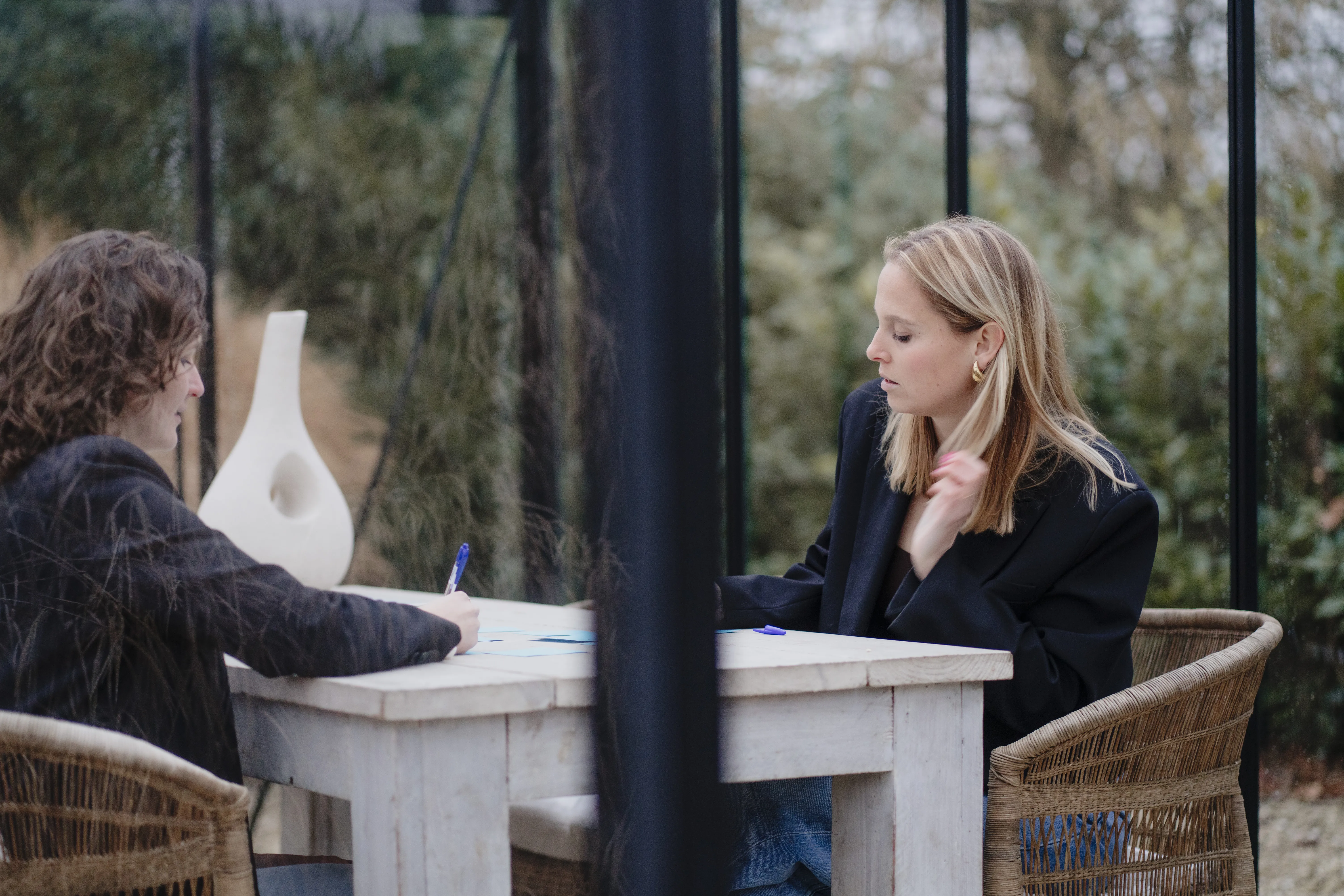 Imke in gesprek in een glazen tuinkamer, met groen eromheen