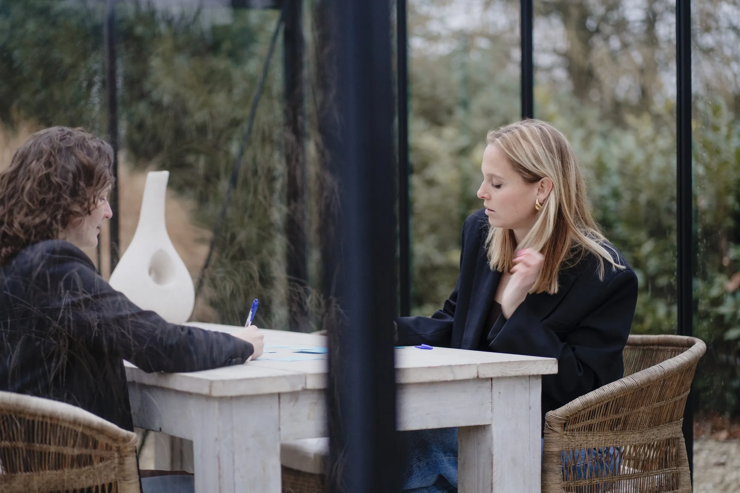 Imke in gesprek in een glazen tuinkamer, met groen eromheen